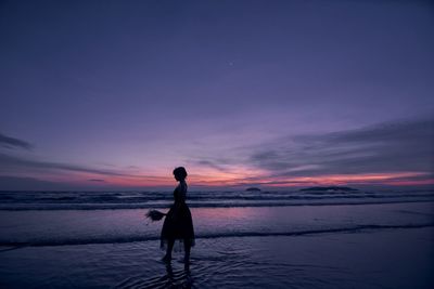 Silhouette man standing on beach against sky during sunset