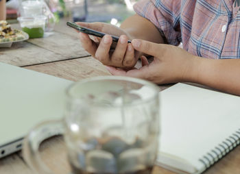 Midsection of man using mobile phone on table