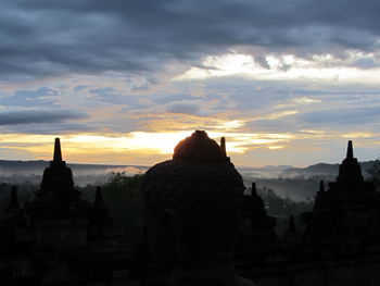 Silhouette of temple against cloudy sky