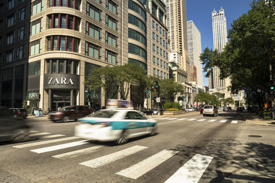 Cars on city street by buildings