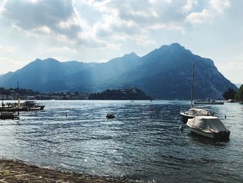 Sailboats moored in sea against mountains