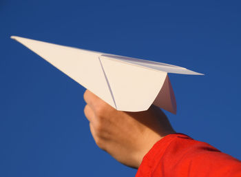 Midsection of man holding paper against blue sky