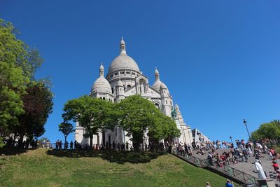 Group of people in front of building against clear blue sky