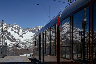 Gornergrat bahn at station through snow landscape with matterhorn in background and swiss clock