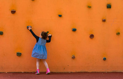 Rear view of girl climbing wall 