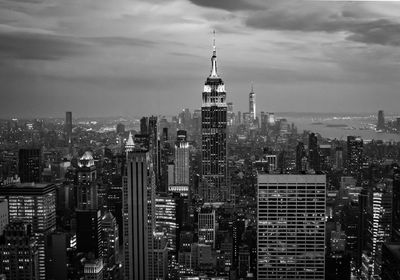 Aerial view of manhattan buildings in city against cloudy sky in black and white