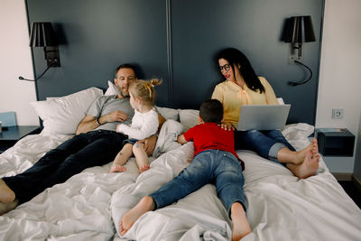 Happy family on bed in hotel room during vacations