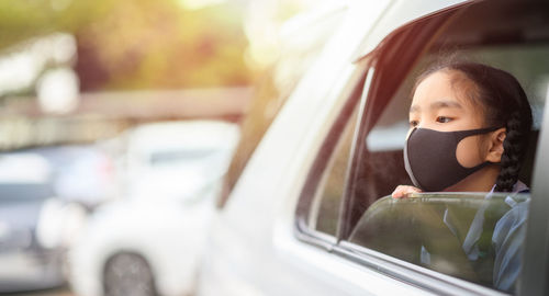 Portrait of cute girl seen through car window