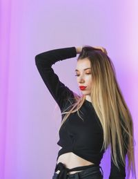 Woman standing against pink background
