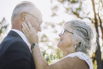 Smiling affectionate senior bride touching groom's cheek