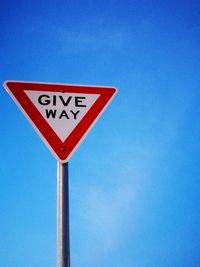 Close-up of road sign against clear blue sky