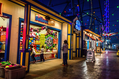 Woman standing by multi colored store at night