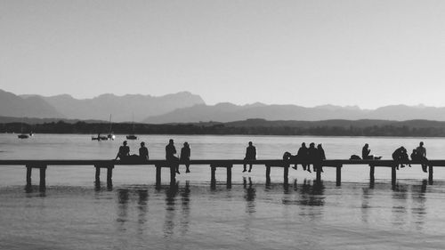 People on riverbank against clear sky