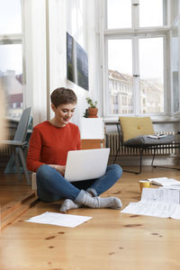 Young woman using phone while sitting on table