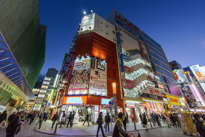 People on illuminated city against sky at dusk