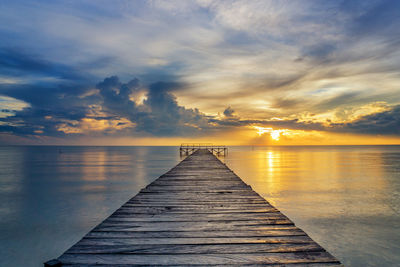 Pier over sea against sky during sunrise