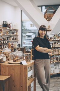 Smiling entrepreneur standing with arms crossed in convenience store