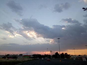 Cars on street against sky at sunset