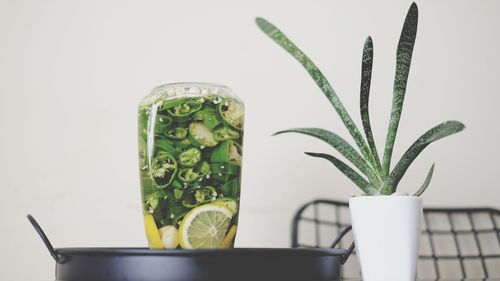 Close-up of potted plant by food in jar over container against wall