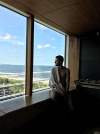 Young man looking through window