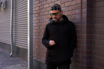 Man smoking cigarette while standing against wall