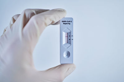 Close-up of person holding camera against white background