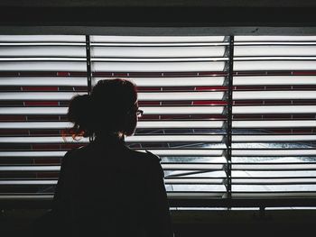 Rear view of woman looking through window