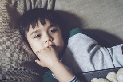 High angle view of cute boy lying on sofa