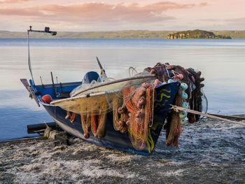 Fishing boat moored on beach against sky