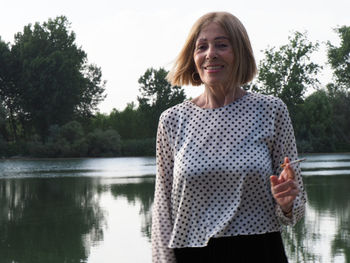 Portrait of young woman standing against lake