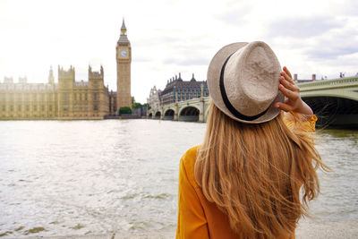 Tourist woman enjoying sight of westminster palace and bridge on thames with big ben tower in london