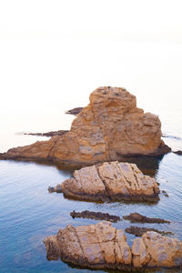 Rock formation in sea against clear sky