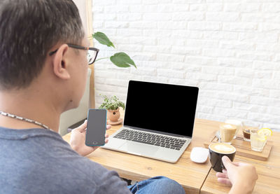 Midsection of woman using mobile phone while sitting on table