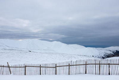 Scenic view of snow covered field against cloudy sky