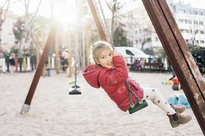 Cute girl playing with swing in playground