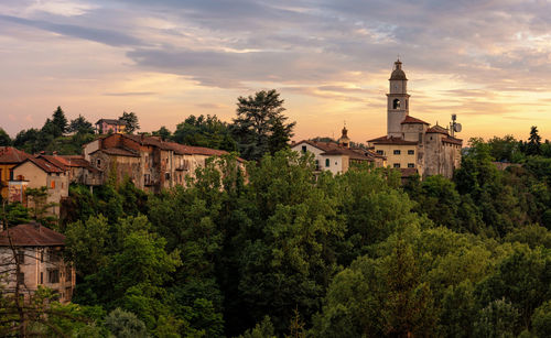 Trees and buildings against sky during sunset