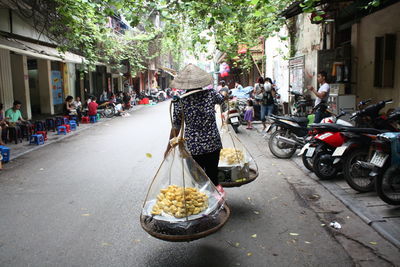 Rear view of jackfruit vendor walking on street