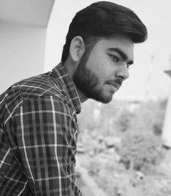 Side view of thoughtful young man looking away while standing outdoors