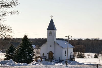 Church by building against sky during winter