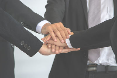 Midsection of colleagues stacking hands in office