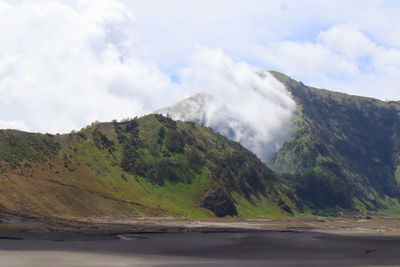 Scenic view of road by mountains against sky
