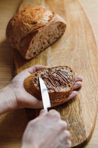 White man's hands spread chocolate or peanut butter on sourdough bread. breakfast or lunch