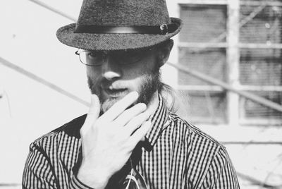 Bearded young man with hand on chin wearing hat during sunny day