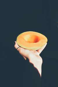 Close-up of hand holding apple against black background