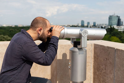 Side view of man against sky in city