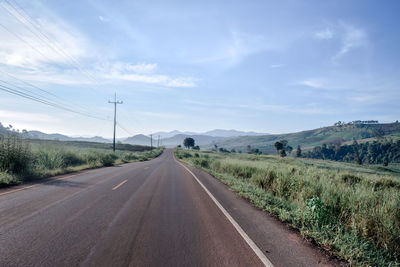 Road amidst field against sky