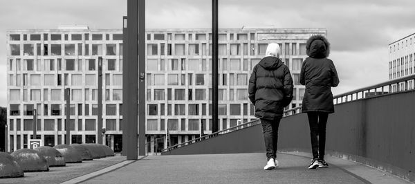 Rear view of men walking on bridge in city