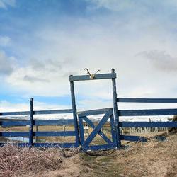 Fence on field against cloudy sky