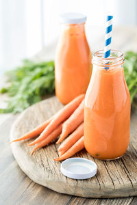 Close up of two bottles of freshly made carrot juice ready for drinking.