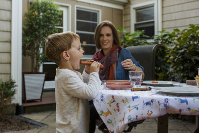 A happy mother watches her son eat dinner